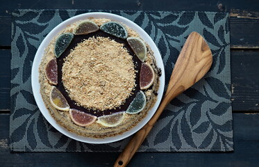 Food background in rustic style.Homemade round honey layered honey cake on a dark background with a wooden kitchen spatula and place for text.