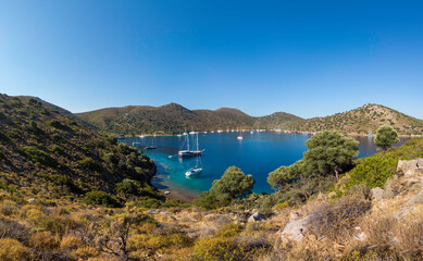 Summer sailing concept: A peaceful bay in the Aegean area with many moored yachts in tranquil...