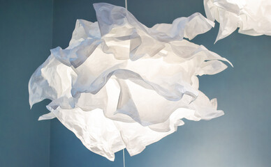 Lamp design made of crumpled paper in the shape of a flower or cloud on a blue background