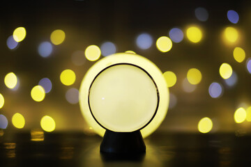 Crystal Ball on the table with bokeh, lights behind. Glass ball with colorful bokeh light, prediction concept.