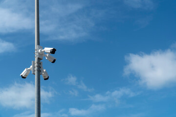 Security systems and alarm technology concept: Many CCTV cameras hanging on a outdoor pol and recording. Digital surveillance. High safety and protection cam and video. Blue sky with copy space.