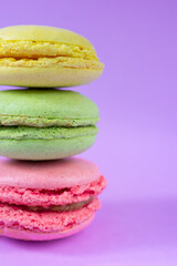 Close up photo of three french cookies with different interlayers one on top of each other on stack on bright purple background, french traditional pastry