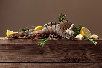 Fresh tiger prawns with lemon, rosemary and garlic on a old wooden table.