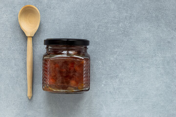 Homemade apple jam in jar with wooden spoon on gray background