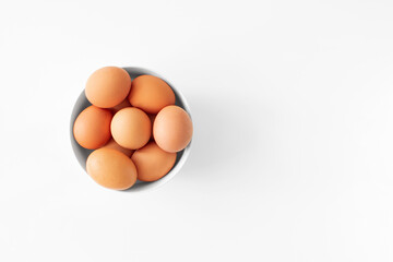 Brown eggs in bowl flat lay on white background top view copy space. Minimalism style easter day. Chicken eggs. Food layout.