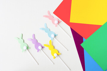 Figures from paper on sticks. Bright paper in different colors on a wooden table. Making decorations with children.