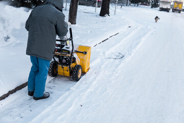 Man cleaning driveway with snow machines after a snow storm. Snow removal equipment working on the...