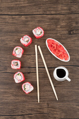 California sushi rolls, pickled ginger and soy sauce on wooden surface