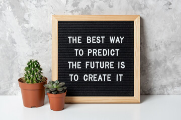 The best way to predict the future is to create it. Motivational quote on letter board, cactus, succulent flower on white table. Concept inspirational quote of the day. Front view