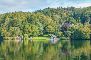 Fototapeta na wymiar The beautiful white house and boathouse stunningly reflected on the lake