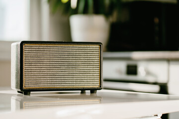 A vintage radio sits on a white table in the kitchen. Accepts the melody via the bluetooth channel. Cheerful music plays loudly. Copy space.