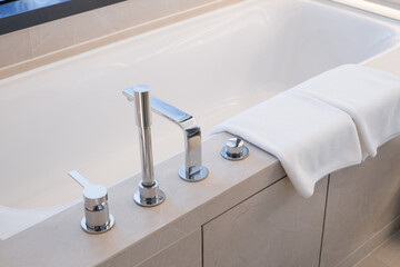 Bathroom bath towels hanging in bathtub. Towel napkin hanging in restroom. White Towel for wiping the hand in the toilet.