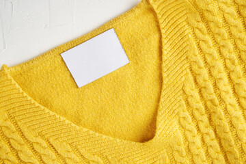 Mockup of an inner label on the neck of a pretty yellow wool sweater. Blank space to place a logo, text or image