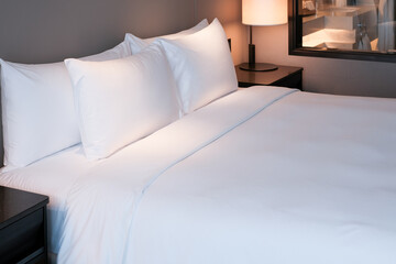 Clean Bedding sheets and pillow on natural wall room background. White bedding and pillow in hotel...
