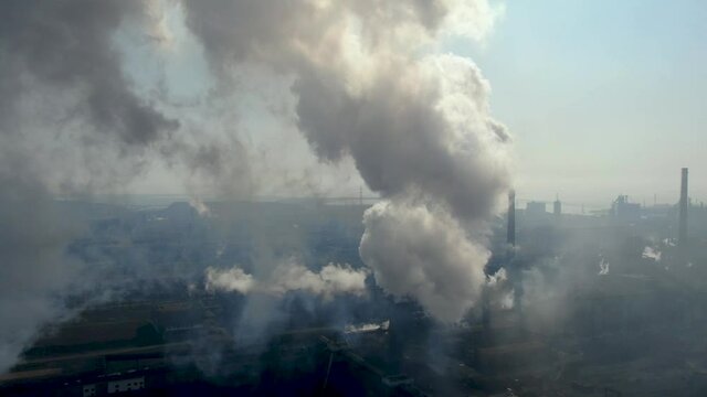 Drone fly around toxic enterprise chimneys tubing against the sky background release smoke. Factory pollutes environment. Aerial view. Ecology disaster. Azovstal. Mariupol, Ukraine