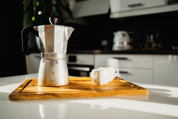 Coffee maker made of aluminum metal. An invigorating delicious drink instead of an energy drink. Ceramic cups of white light coffee. A hot, flavorful drink. Espresso Americano is on the table.