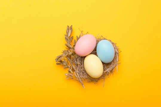 Close up photo of birds nest easter eggs over yellow background.