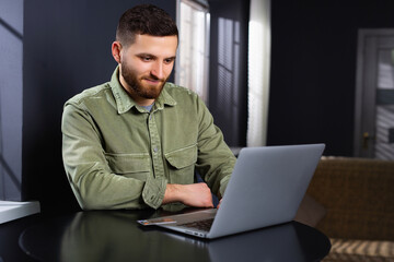 Young caucasian male businessman working at home using laptop. Telework. Work online.