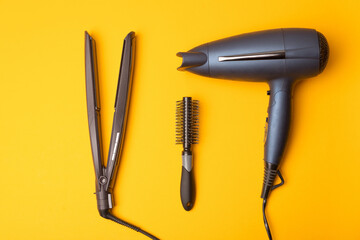 Photo of hair dryer and accessories over yellow background.