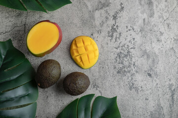 Sliced mango and ripe avocado fruits on marble surface
