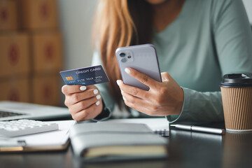 Close up woman hand using credit card and smartphone laptop for buying online shopping at home,