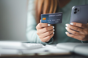 Close up woman hand using credit card and smartphone laptop for buying online shopping at home,