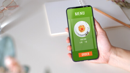 Close up hand order food online with mobile apps on table sitting at home top view,online order concept