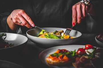 woman eating healthy salad from bowl sitting in cafe