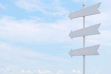 White painted wooden sign with an arrow pointing out on sky
