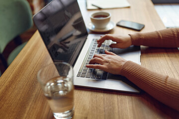 Woman working on laptop with cup of coffee on table