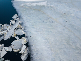 Ice melts on the river. Ice crack. Aerial drone view. Spring sunny morning.