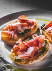 Bruschetta with prosciutto and pesto sauce on plate