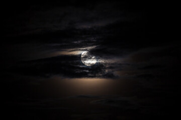 Full moon behind clouds on black sky, dramatic sky, horror sky