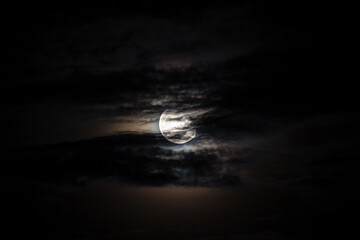 Full moon behind clouds on black sky, dramatic sky, horror sky