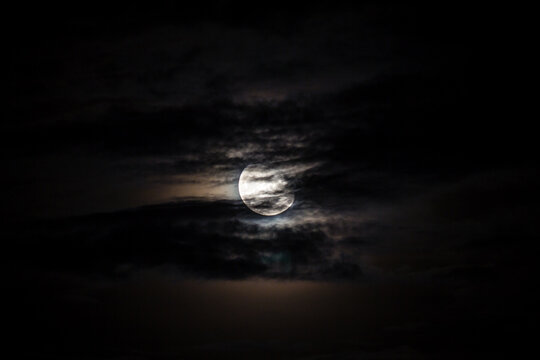Full moon behind clouds on black sky, dramatic sky, horror sky