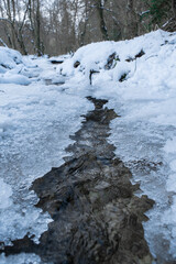 Fototapeta na wymiar Water flowing in partially frozen creek