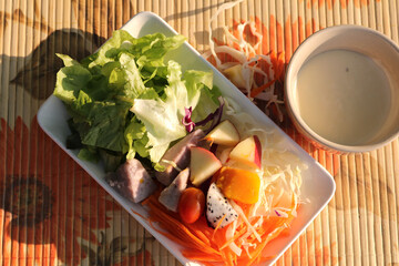 Fototapeta na wymiar Mixed fruit and vegetable salad in many fresh dishes is a healthy meal with warm morning sunshine, adding a more appetizing atmosphere.