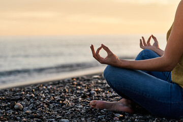 Hands of unrecognizable woman meditating on the beach. Concept of relaxation, meditation and yoga. - 416924813