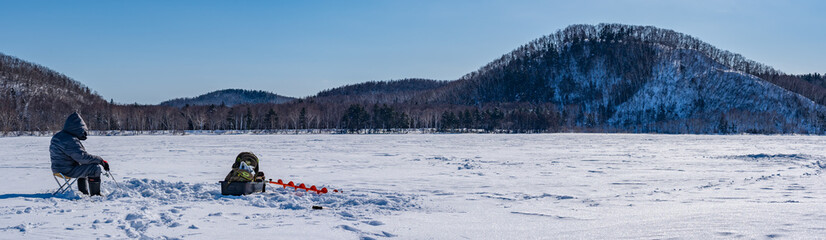 Sakhalin, Russia - 02.27.2021: People catch fish on a frozen lake. Winter fishing