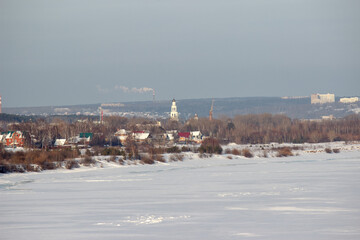 Naklejka premium A small settlement with a towering bell tower on the bank of a frozen river.