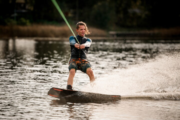 young cheerful guy actively spends his leisure time and rides wakeboard.