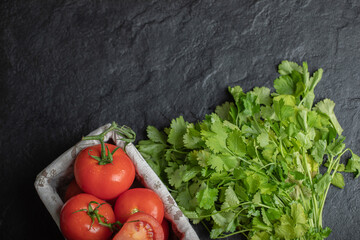 Top view of fresh ripe tomatoes in basket and coriander leaves