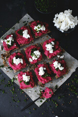 Baked Beetroot Hummus on toasted bread. Dark background, selective focus. Vegan recipes, plant-based dishes. Green living concept. Organic food. Vegetarian cuisine. 