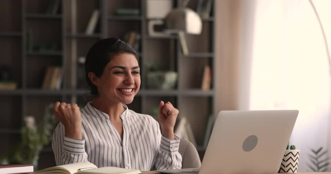 Euphoric young indian ethnicity woman looking at laptop screen, reading email with unbelievable good news, getting dream job offer, excellent professional test results or win success notification.