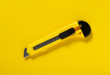Construction or office knife on a yellow background. Used for cutting objects