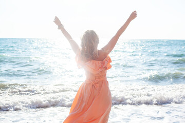 Fototapeta na wymiar Beautiful woman in maxi dress walking in the beach of the sea