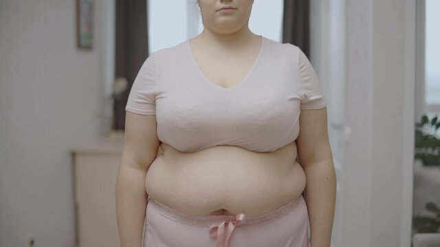 Sad overweight woman touching belly fat, weight loss diet, physical inactivity