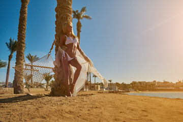 beautiful woman standing near the palm tree on the beach