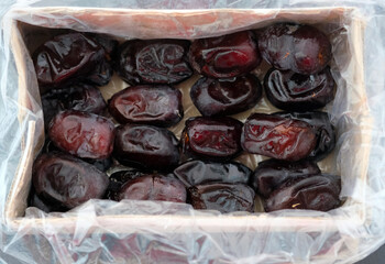 Large dates in a cardboard box top view. Packaged Iranian dates. Dried fruits are sweet for tea.