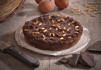 Chocolate nuts cake on rustic kitchen and ingredients.